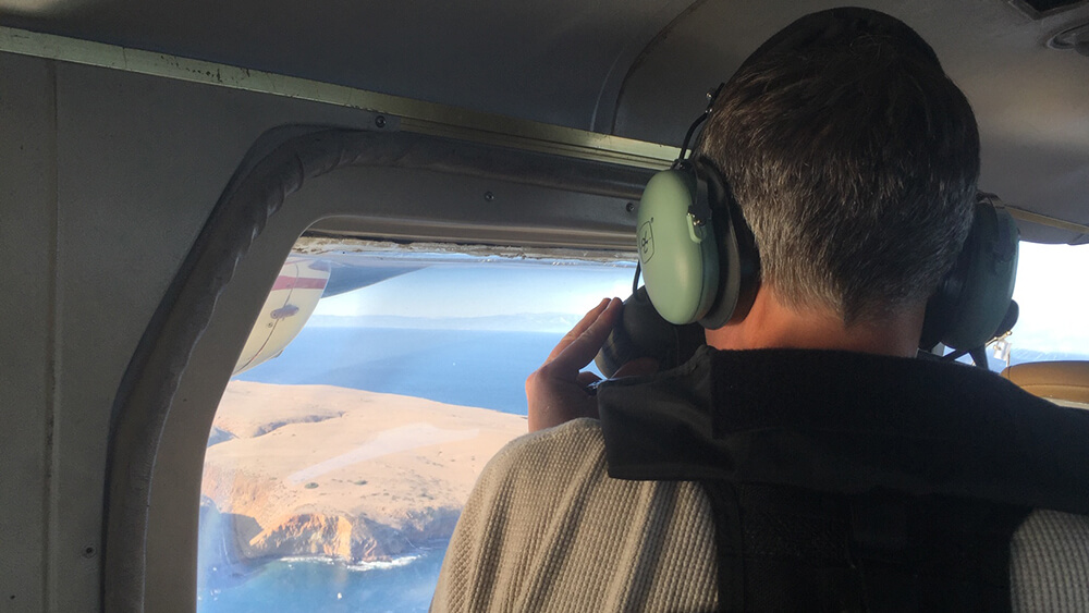 a person looks out of a plane window over channel islands national marine sanctuary