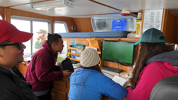 people look at a monitor onboard a boat
