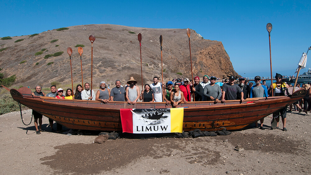people on a beach with a traditional Chumash tomol